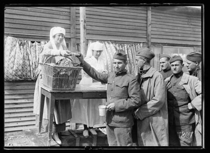 Miss Cotton handing out bread to a line of American soldiers at the American Red Cross line-of-communicatio…