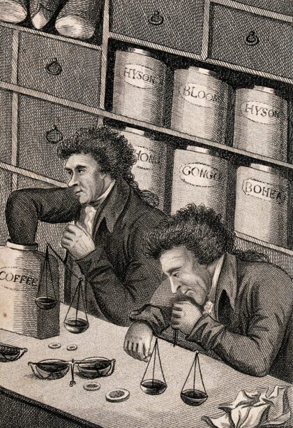 Two men at a shop counter in a tea and coffee retail shop using scales to measure out coffee beans. Engravi…